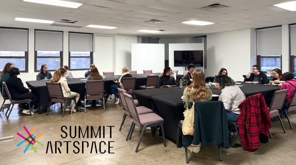 People sitting around tables eating food in a classroom. Summit Artspace Logo is in the bottom left corner.